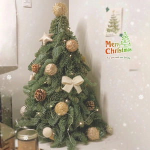 Mini green Christmas tree with gold ornaments, bows, and warm LED lights on a tabletop