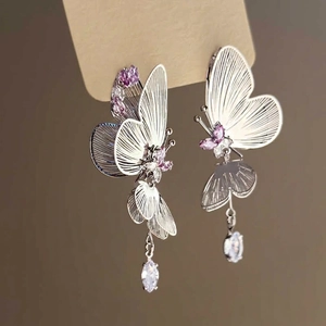 Detail of silver butterfly earrings with purple zircons and delicate filigree wings