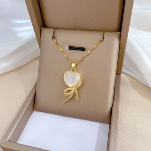 Close-up of golden bow pendant necklace with shiny crystals in a beige luxury gift box