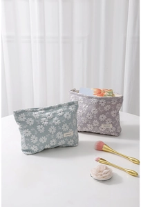 Détail de trousses à maquillage en toile avec broderie marguerite et fermetures éclair