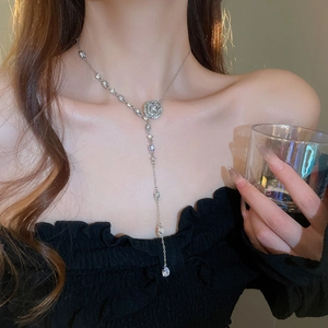 Detail of silver flower tassel necklace with crystal pavé and waterdrop pendant on neck