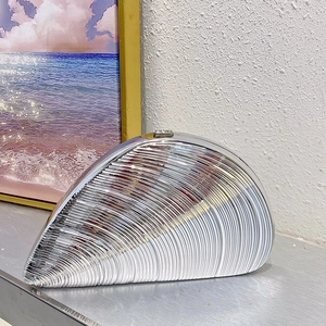 Detail shot showing the wavy metallic texture of a silver shell-shaped evening clutch bag