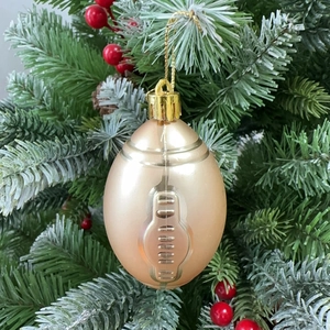 Close-up of golden football-shaped ornament hanging on a festive decorated Christmas tree