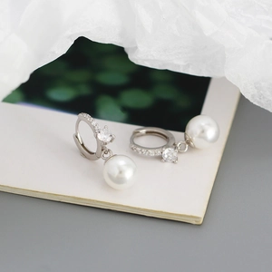 Detail view of silver leverback earrings with small cubic zirconia and white round pearls