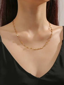 Detail of gold heart pendant and textured oval beads on stainless steel chain
