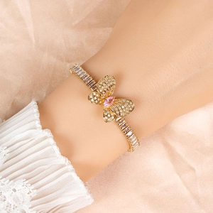 Elegant gold butterfly bracelet with pink gemstone and white zircon stones on silk background