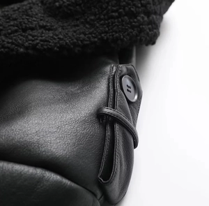 Detailed close-up of matte black leather and plush faux shearling lapel on winter coat