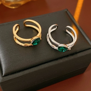 Détail de la bague croisée dorée avec zircon vert sur boîte à bijoux noire