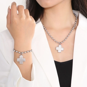 Detail of silver beaded chain necklace and bracelet set with cross pendants on a model