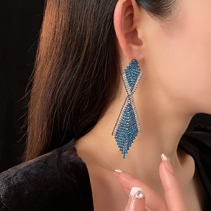 Nahaufnahme geometrischer Quastenohrringe mit blauen und silbernen Strasssteinen am Model