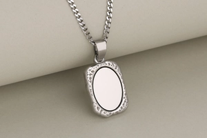 Macro shot of silver rectangular pendant with textured border and polished blank center