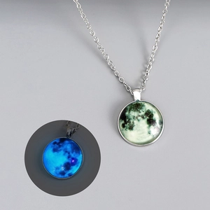 Detailed view of glowing moon pendant necklace showing luminous blue effect in the dark