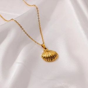 Gold scallop shell pendant necklace in stainless steel on a white silk background