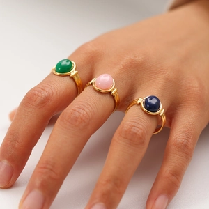 Close-up of vintage gold stainless steel rings with colorful natural stones on fingers