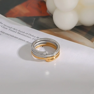 Dettaglio anello a spirale bicolore in oro e argento in acciaio inox su sfondo lifestyle