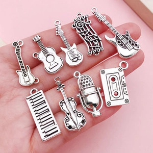 Close-up of nine silver music-themed charms including guitar, violin, and microphone