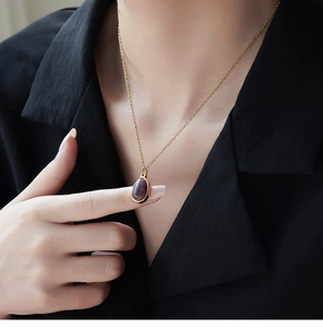 Close-up of geometric purple quartz pendant on 18K gold plated necklace chain