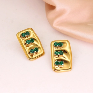 Detailed view of gold rectangle stud earrings with triple green rhinestones on silk fabric
