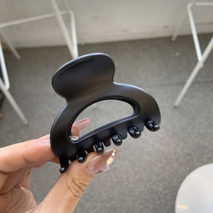 Detail of matte black shark hair clip showing the semi-circular hollow design and finish