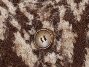 Dettaglio macro del tessuto a maglia mohair marrone con un bottone in resina coordinato