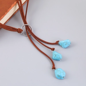 Detail of bohemian long turquoise necklace with brown suede cord and silver metal ring