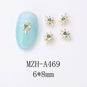 Détail d'un bijou d'ongle étoile dorée 6x8mm avec strass bleu sur un ongle bleu clair