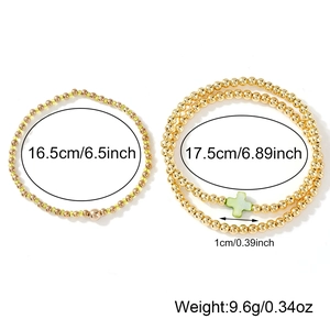 Stackable gold beaded bracelet set with a shell cross charm and size measurements