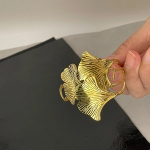 Detailed view of adjustable golden ginkgo leaf cuff bracelet with polished finish