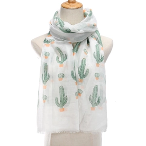 Lightweight white scarf with green cactus print and tassels on wooden mannequin