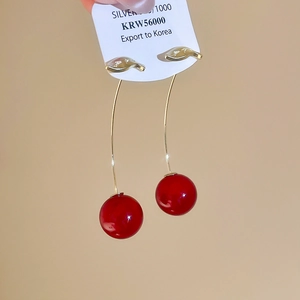 Detailed close-up of elegant resin cherry earrings with golden hooks and glossy red spheres