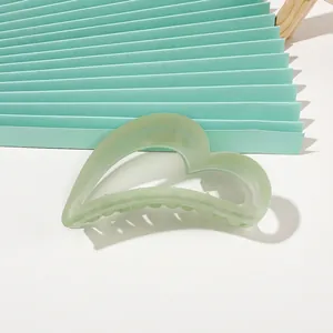 Detailed view of matte mint green heart-shaped shark hair claw clip on soft backdrop