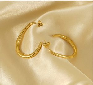 Close-up of golden U-shaped stainless steel earrings on elegant silk background