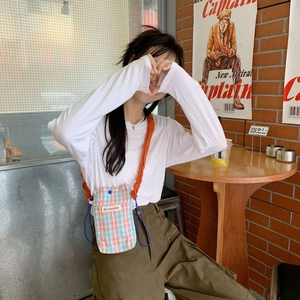 Close-up of a colorful plaid canvas crossbody phone bag with an orange strap and blue drawstring