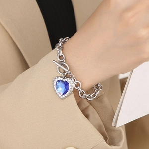 Detail of silver OT buckle chain bracelet with a heart-shaped blue crystal pendant
