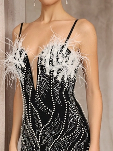Détail d'une robe de soirée noire avec plumes blanches, perles et paillettes ondulées