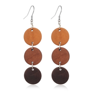 Detailed close-up of brown wooden geometric earrings with triple circular gradient discs