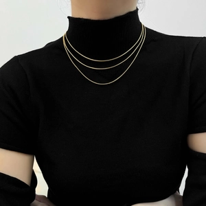 Detailed view of 18K gold plated snake chain layered necklace worn on a neck