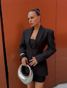 Detail of black corset waist blazer featuring a sharp lapel and slim fit design