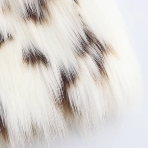 Macro shot of faux fur texture with white and brown spots on the plush jacket fabric