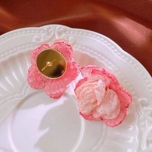 Detailed macro view of pink lace flower earrings with layered fabric petals on ceramic plate