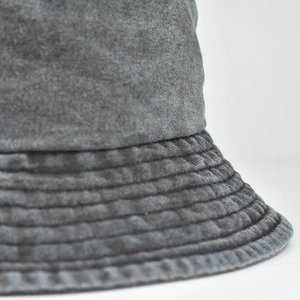 Dettaglio macro delle cuciture rinforzate multi-fila sulla tesa del cappello a secchiello grigio