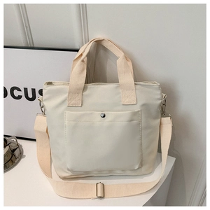 Detalle de bolso tote grande beige en tela oxford con bolsillo frontal y correa ajustable
