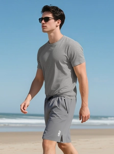 Men's grey fitness t-shirt and dark grey shorts set shown in a sunny beach outdoor setting