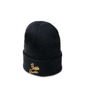 Close-up of black beanie with yellow Selfie Queen crown embroidery and knit texture