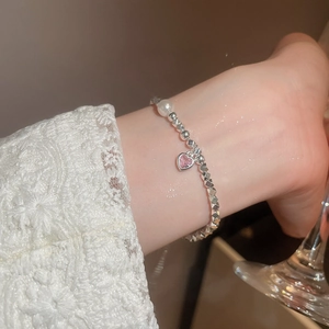 Dettaglio del braccialetto con ematite, perla e ciondolo a cuore rosa su pizzo elegante