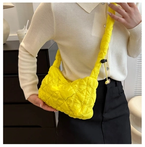 Detail of a bright yellow quilted puffy shoulder bag with adjustable drawstring strap