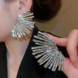 Macro detail of geometric fan earrings featuring sparkling rhinestones on model's ear