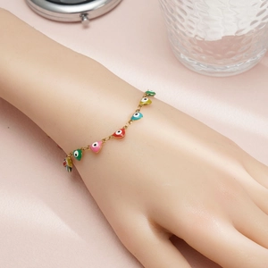 Golden heart charm bracelet with evil eye patterns in vibrant colors on a female wrist