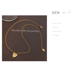 Detailed shot of a gold heart pendant necklace featuring an inset milky cat eye stone