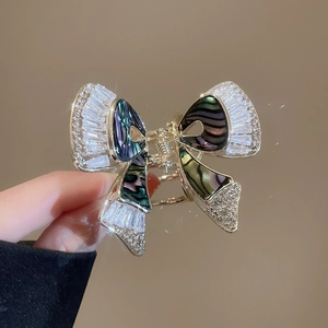 Dettaglio della molletta a farfalla dorata con zirconi e inserti in madreperla colorata